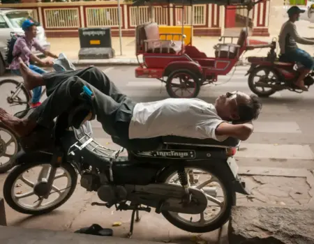 Man sleeping on a motorcycle on a city street