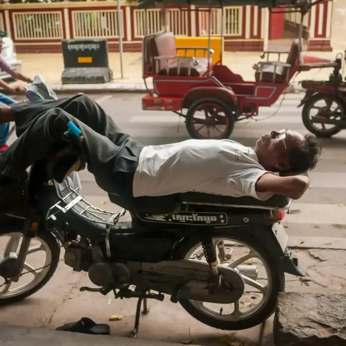 Man sleeping on a motorcycle on a city street