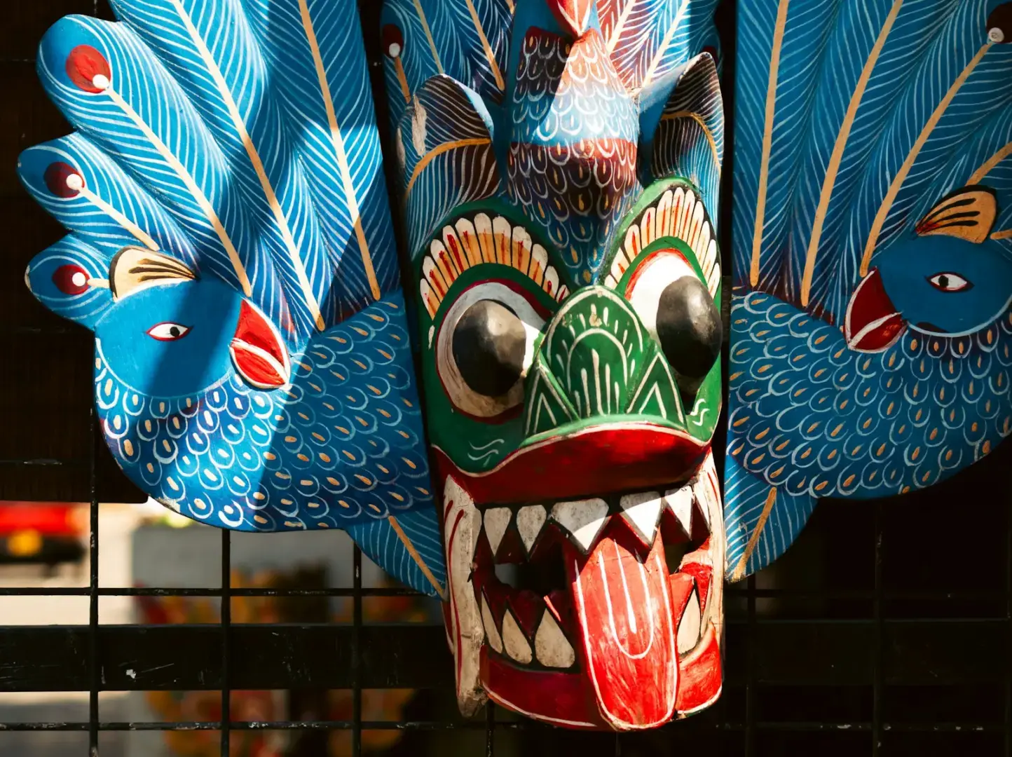 Colorful wooden mask with fierce expression and peacock feathers