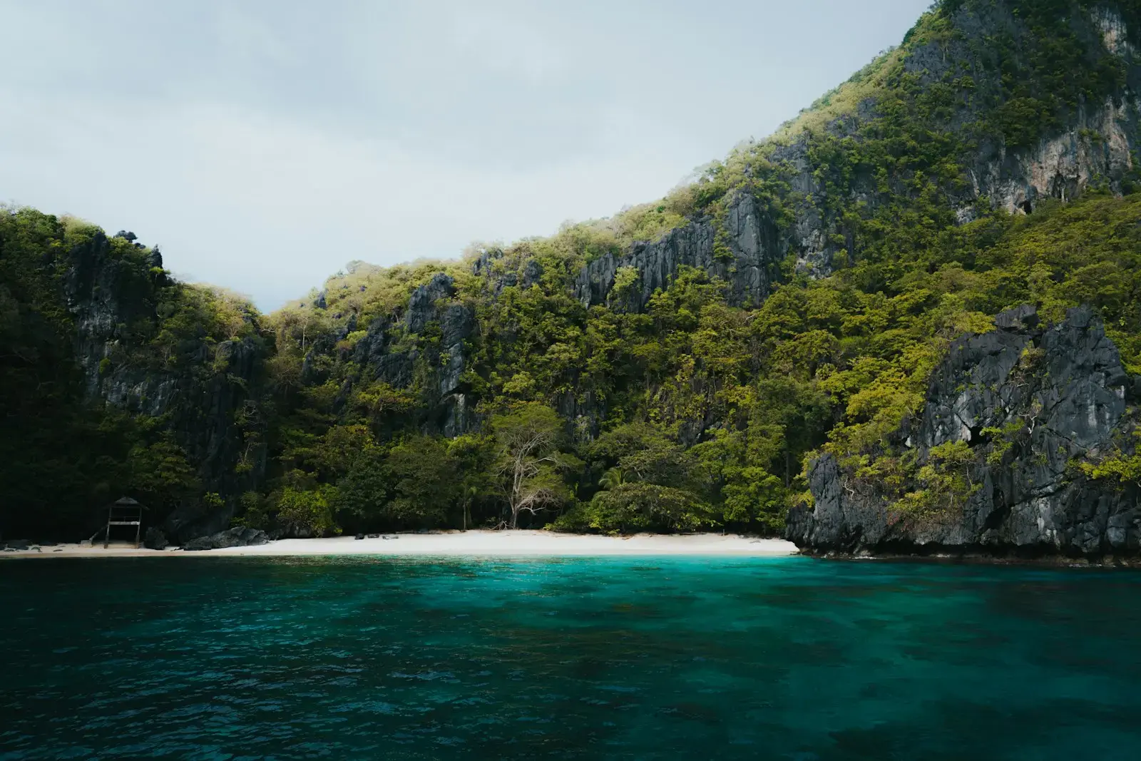 A beautiful beach lies between two rocky mountains.