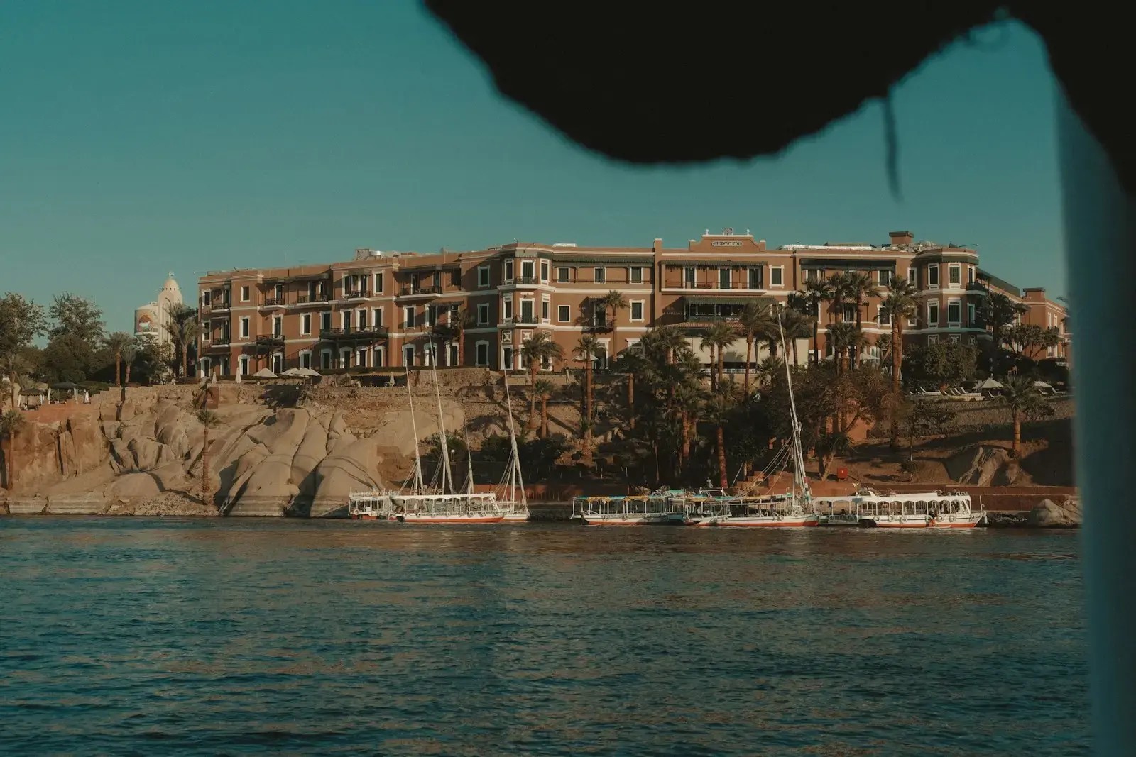 Large hotel on a cliff overlooking boats on the nile