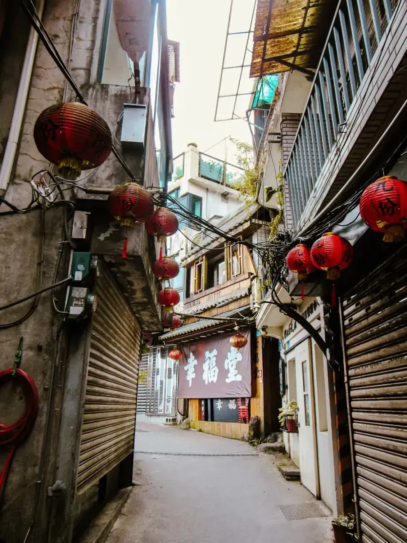 Narrow alleyway lined with shops and red lanterns.