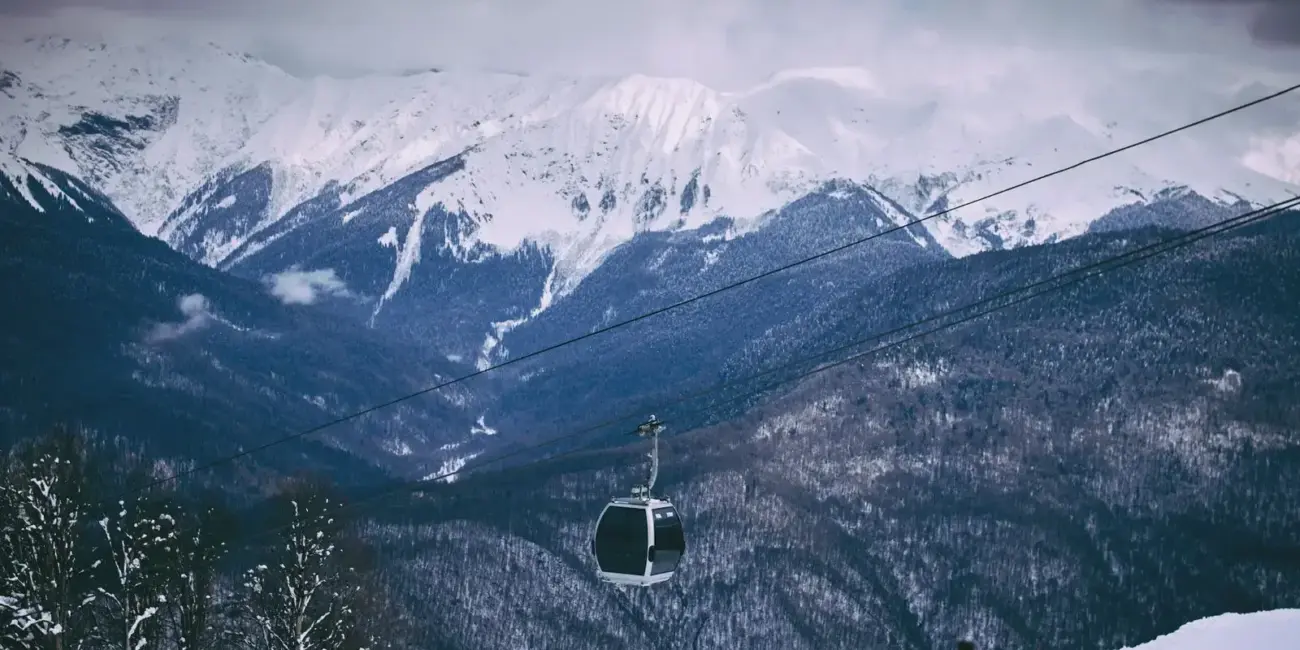 Scenic view of snow-capped mountains with a cable car in a winter ski resort setting.