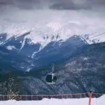 Dovolenka v Rusku na vlastnú päsť Scenic view of snow-capped mountains with a cable car in a winter ski resort setting.