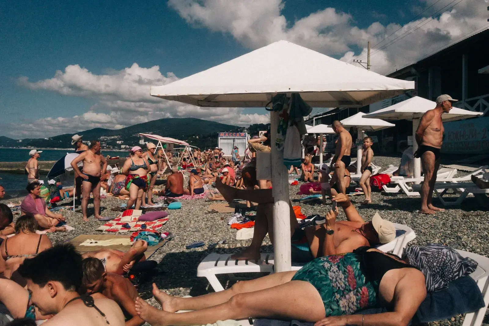 Photo by Anton Belitskiy Crowded beach scene in Sochi, Russia with sunbathers and umbrellas on a sunny day.