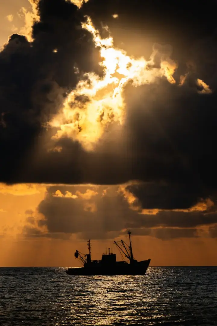 A boat floating in the ocean under a cloudy sky