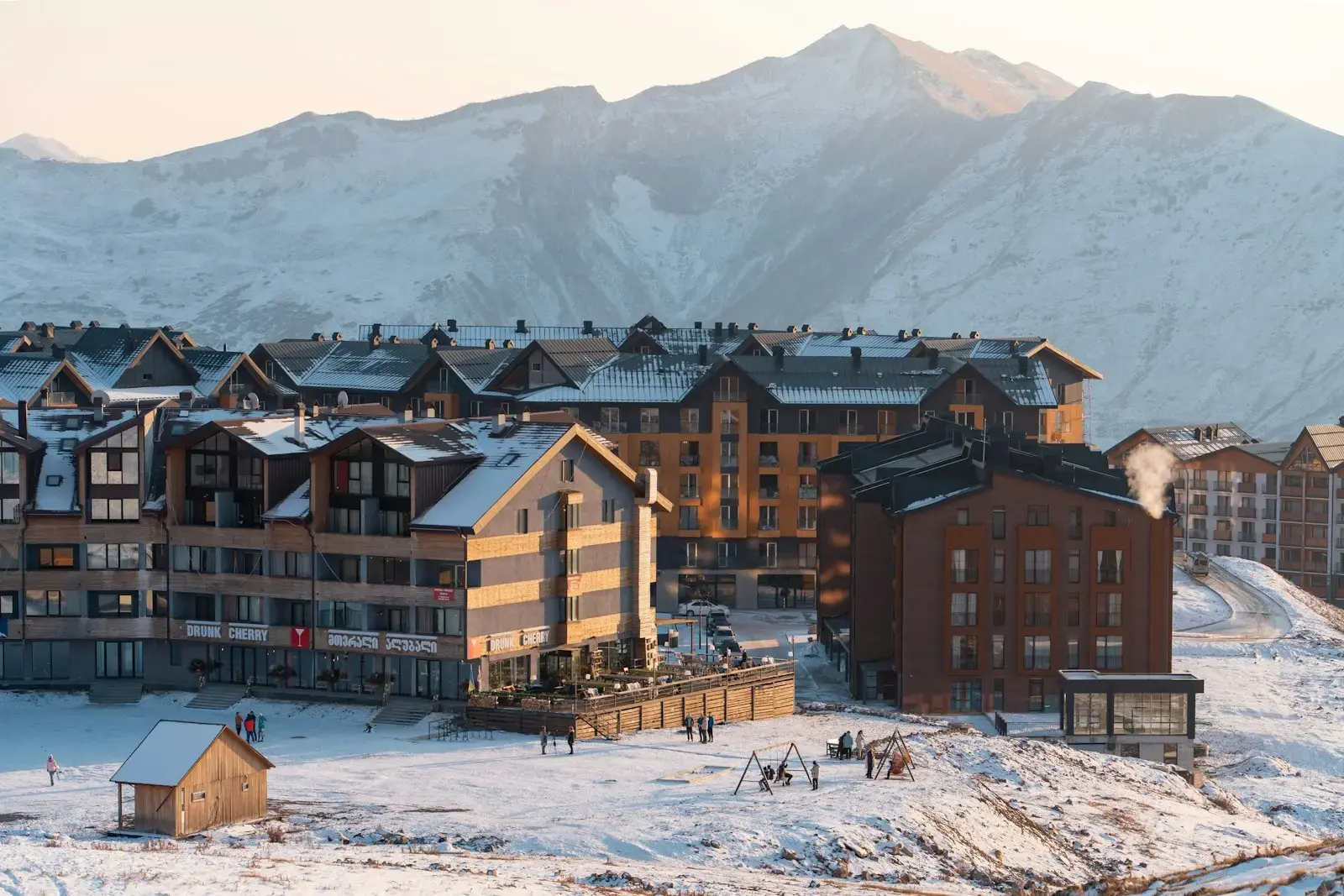 Photo by Albert Canite a group of buildings in the snow with mountains in the background