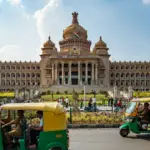 Tuk-tuks drive past a grand government building.