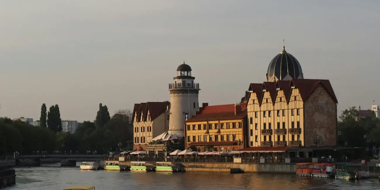 A boat traveling down a river next to tall buildings