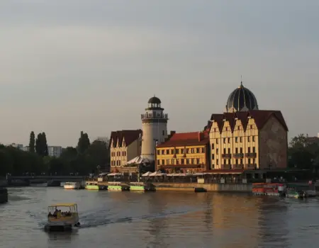 A boat traveling down a river next to tall buildings