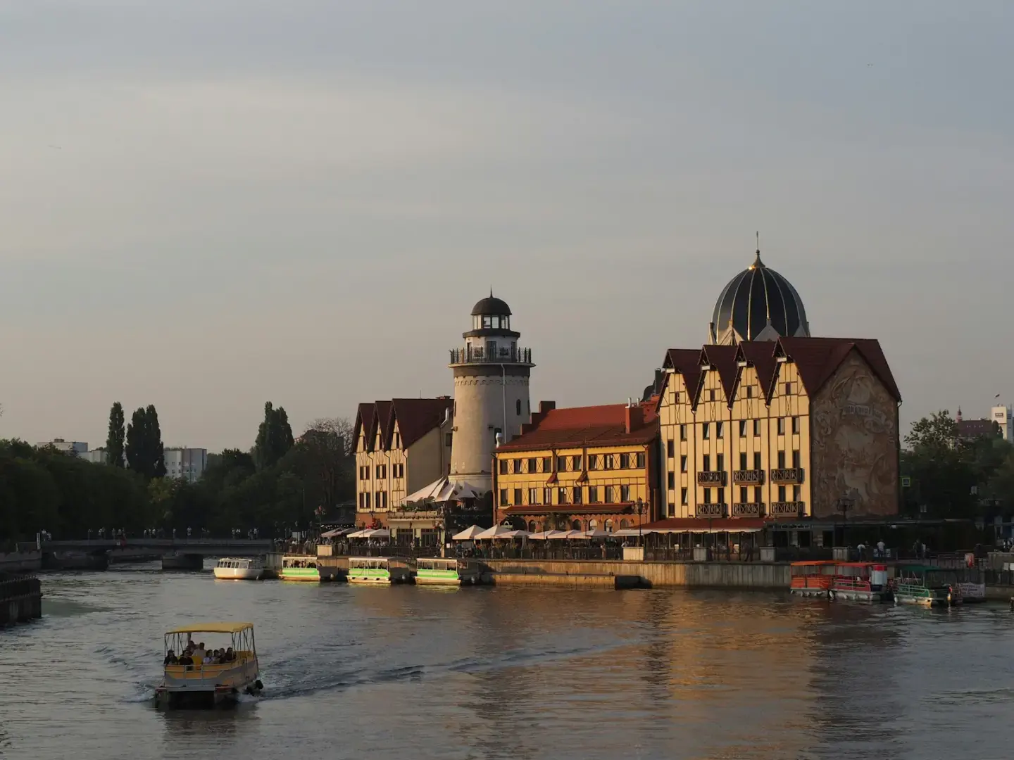 Photo by Evgeniy D. A boat traveling down a river next to tall buildings