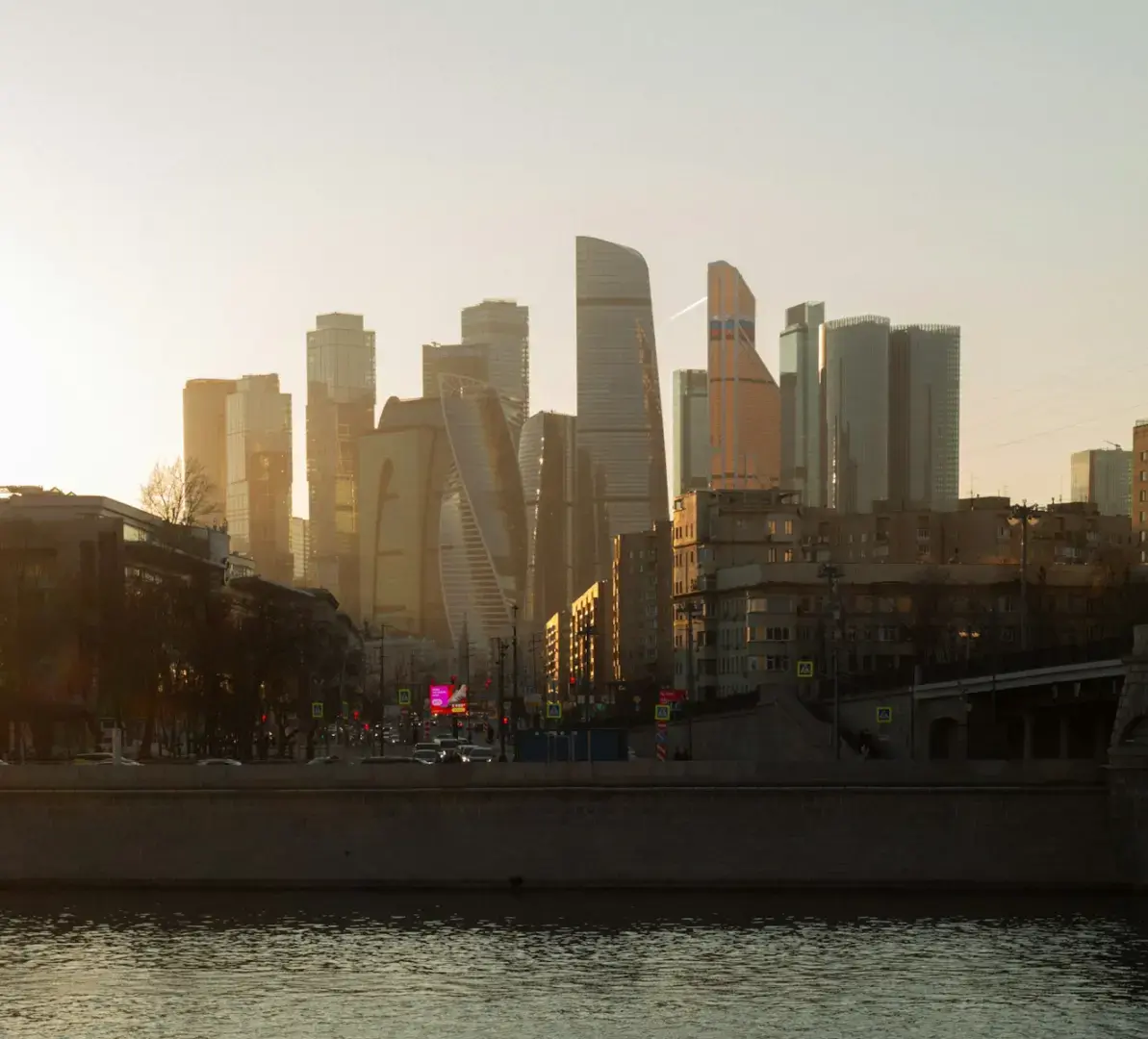 Photo by Ivan Baton Modern skyscrapers line the river at sunset.