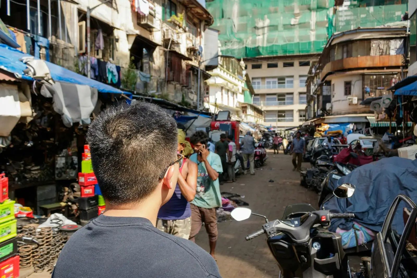 Busy street market with motorcycles and stalls.