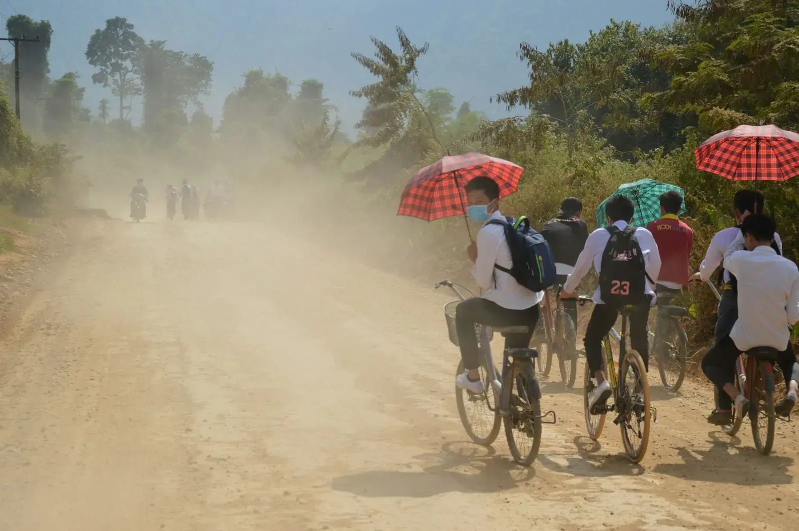 a group of people riding bikes on a dirt road