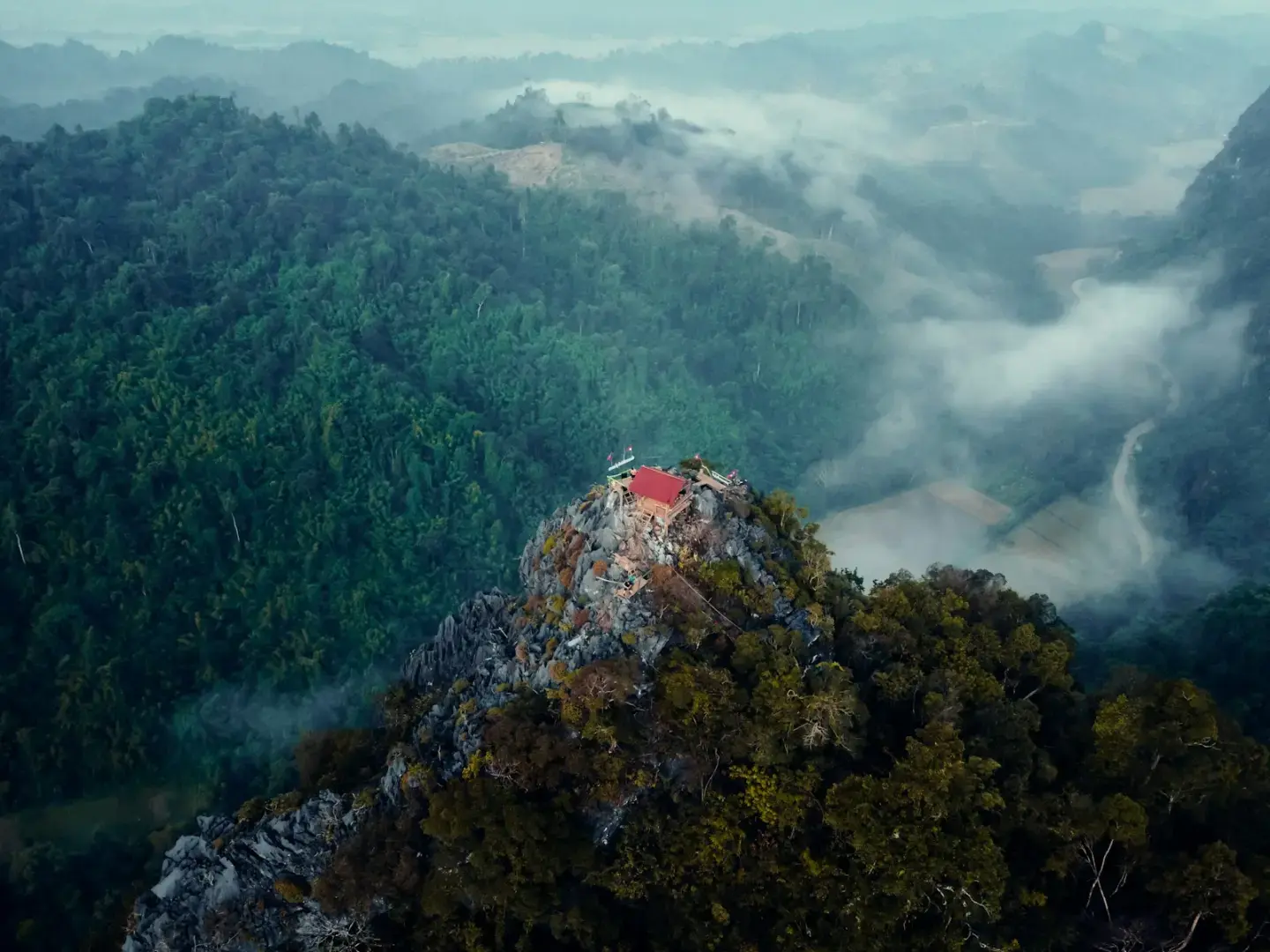 Photo by Simon PALLARD a red building on top of a mountain surrounded by trees