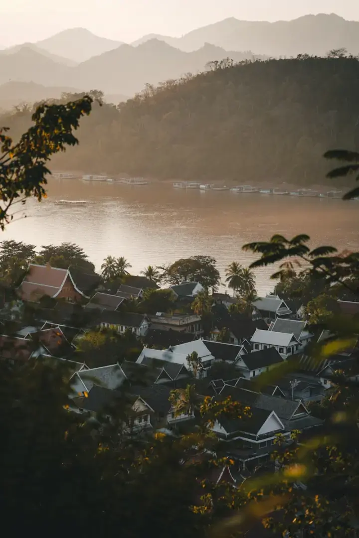 Photo by Kevin Charit Village nestled by a wide river with mountains beyond