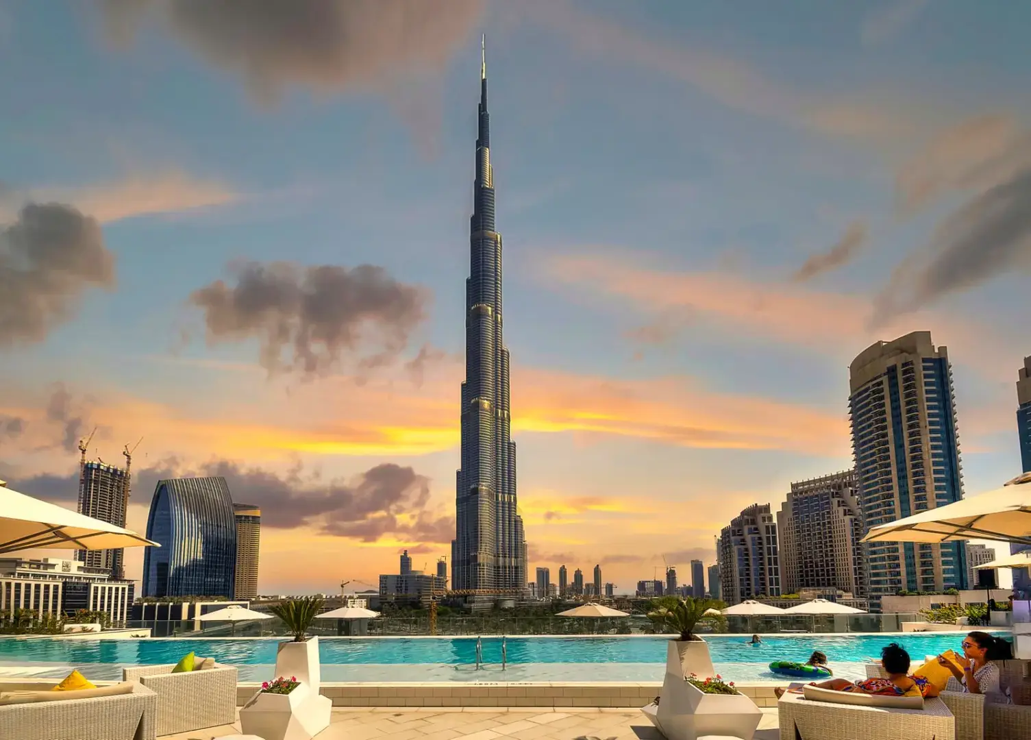 Stunning view of the Burj Khalifa and Dubai skyline from a rooftop pool at sunset.