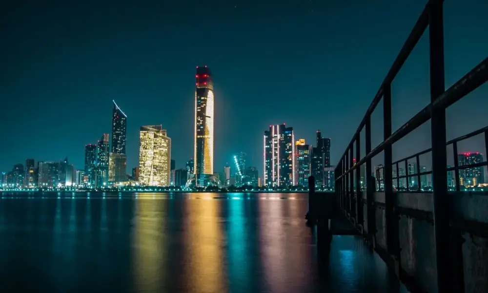 Stunning Abu Dhabi skyline at night with city lights reflecting off the calm waterfront.