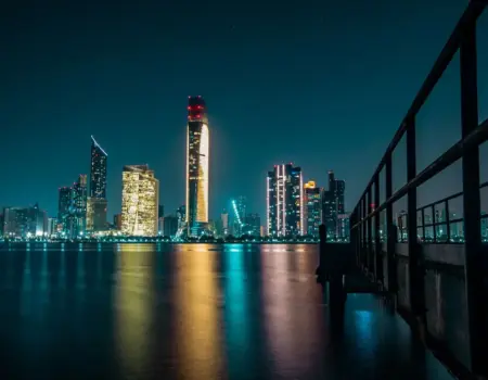 Stunning Abu Dhabi skyline at night with city lights reflecting off the calm waterfront.