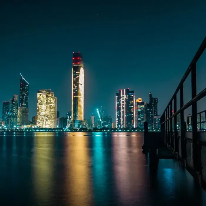 Stunning Abu Dhabi skyline at night with city lights reflecting off the calm waterfront.
