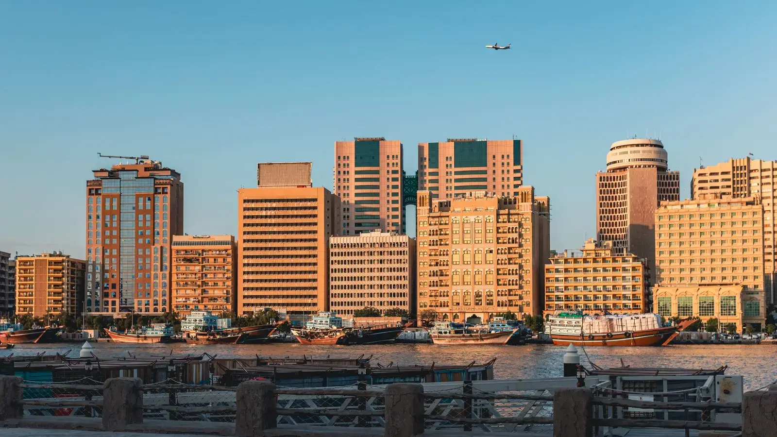 Enchanting sunset view of the Dubai Creek waterfront showcasing modern skyscrapers and traditional boats.