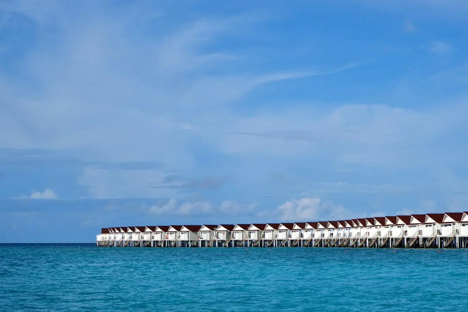 Overwater bungalows line a calm turquoise ocean