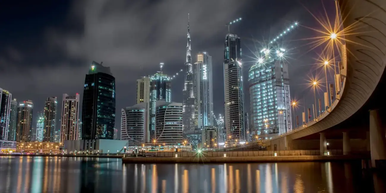 Stunning night view of Dubai's illuminated skyline featuring the iconic Burj Khalifa and waterfront reflections.