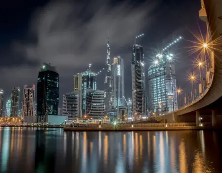 Stunning night view of Dubai's illuminated skyline featuring the iconic Burj Khalifa and waterfront reflections.