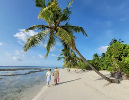 Couple walking on a tropical beach with palm trees