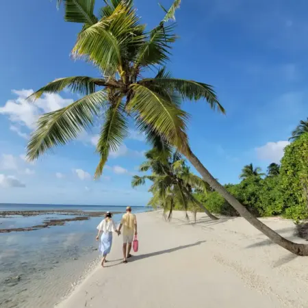 Couple walking on a tropical beach with palm trees