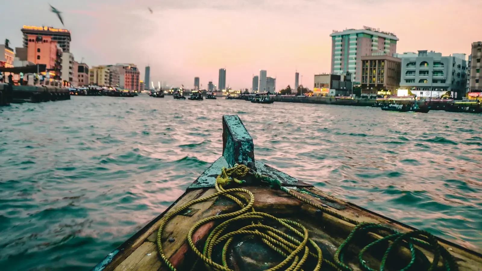 Boat sailing on a river with city skyline at sunset