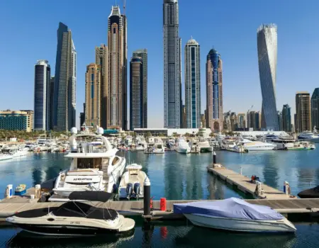 Boats and skyscrapers line a beautiful harbor.