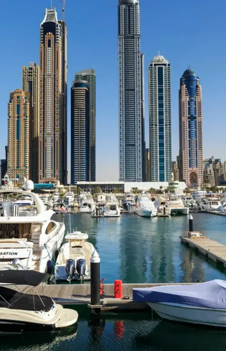 Boats and skyscrapers line a beautiful harbor.