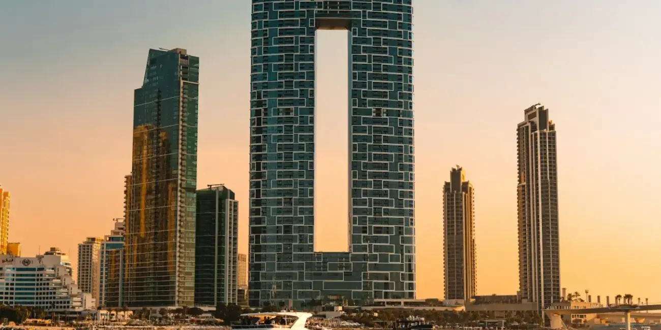 Modern skyscrapers and yachts on the water at sunset.