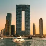 Modern skyscrapers and yachts on the water at sunset.
