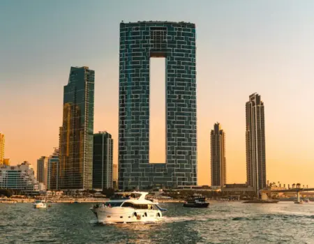Modern skyscrapers and yachts on the water at sunset.