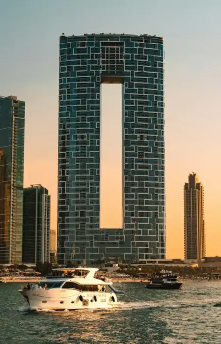 Modern skyscrapers and yachts on the water at sunset.