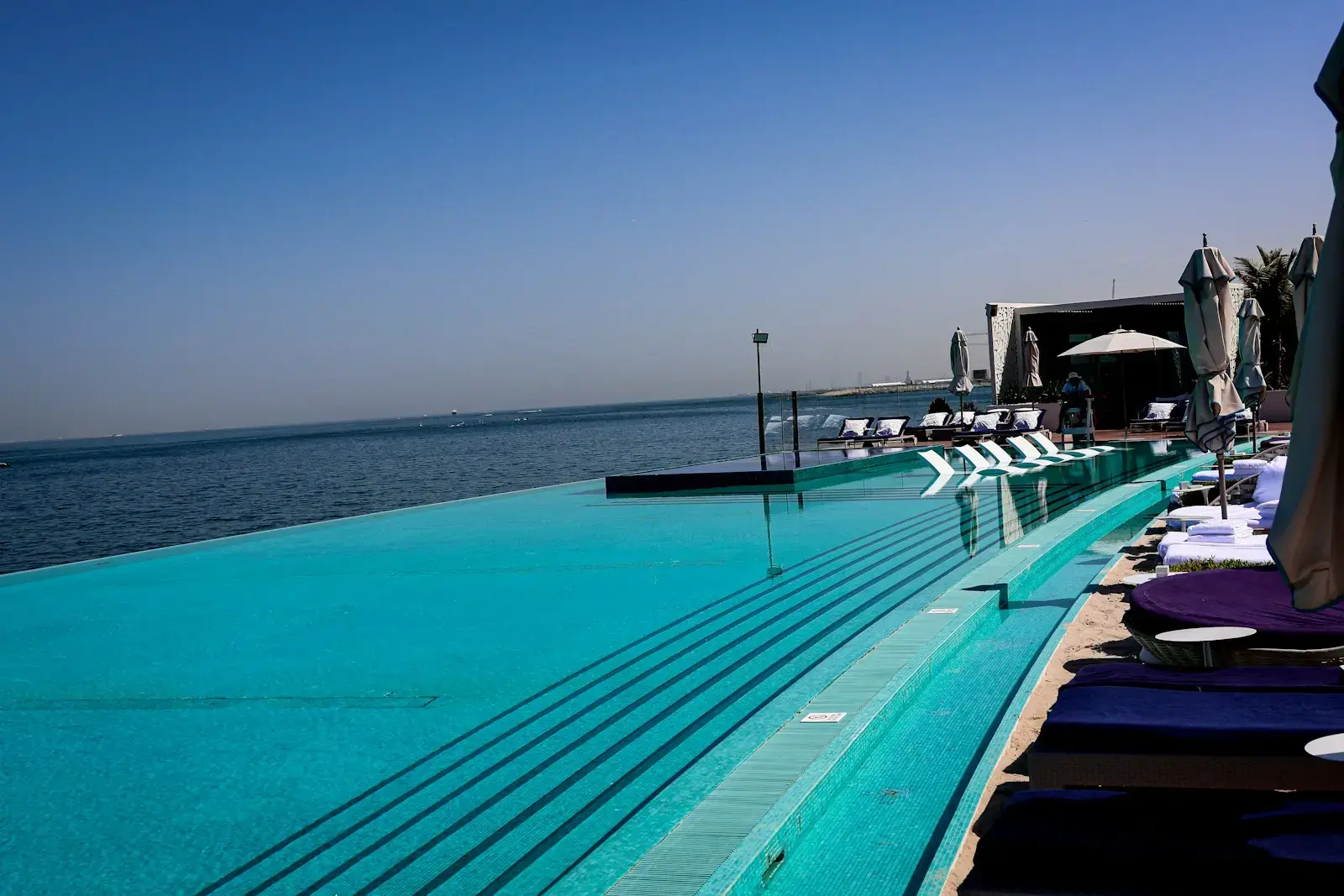 An infinity pool overlooks the ocean on a sunny day.