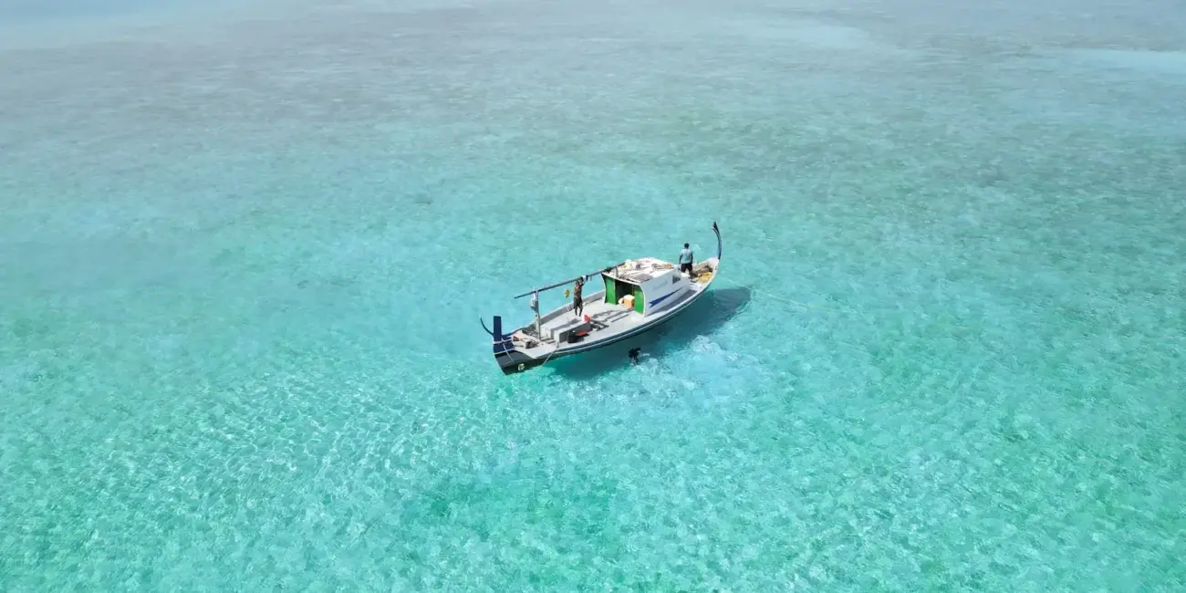 A sailboat floats on clear turquoise water