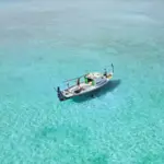 A sailboat floats on clear turquoise water