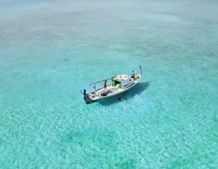 A sailboat floats on clear turquoise water