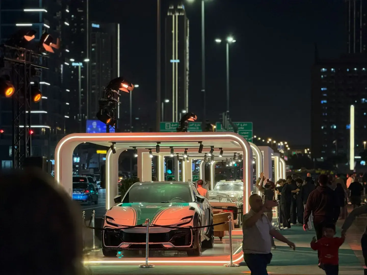 Photo by arshan Latheef Luxury car on display at night in a vibrant city.