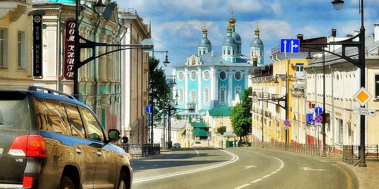 A dark SUV on a city street leading toward a blue and white cathedral